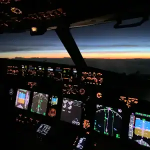 Aircraft cockpit with illuminated controls during sunset, showcasing advanced avionics and navigatio.